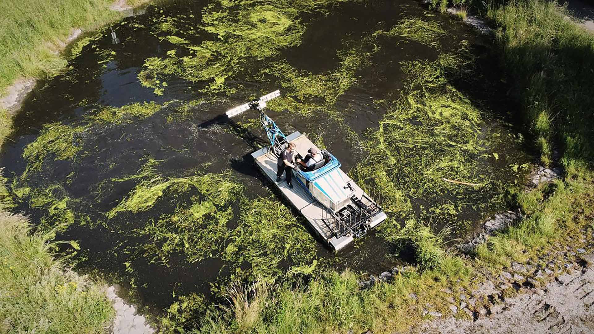 Eine Reinigungsmaschine fährt durch ein dunkles, trübes Gewässer und entfernt dort Verunreinigungen im Wasser.